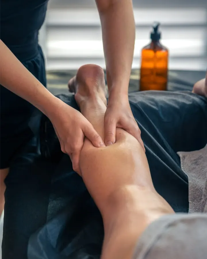 Massagem esportiva na panturrilha de um cliente com roupa de treino