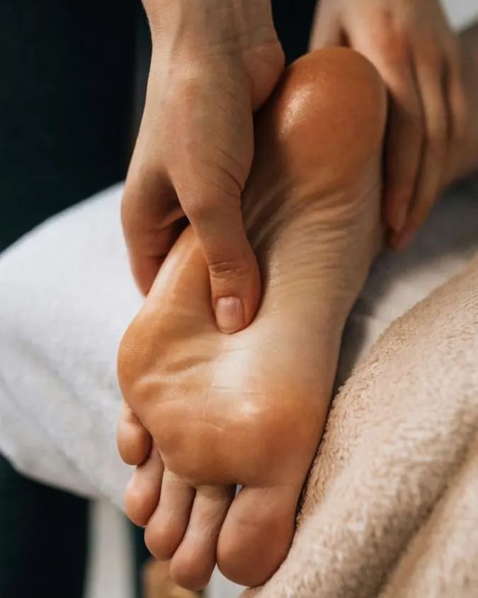 Reflexologia podal: pressão com o polegar na sola do pé